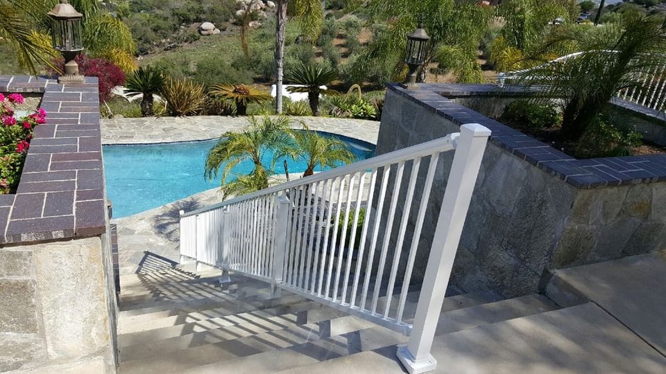 White aluminum railing beside a slate walkway and pool